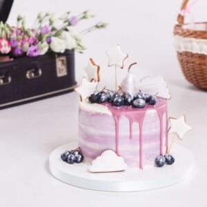 French mousse cake covered with lilac glaze on table. Purple modern European dessert with fruit decoration.