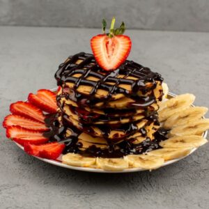 front-view-choco-pancakes-with-red-sliced-strawberries-bananas-inside-plate-grey-floor